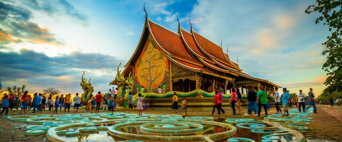 A traditional Thai temple with a curved roof and ornate decorations, surrounded by a circular water feature.