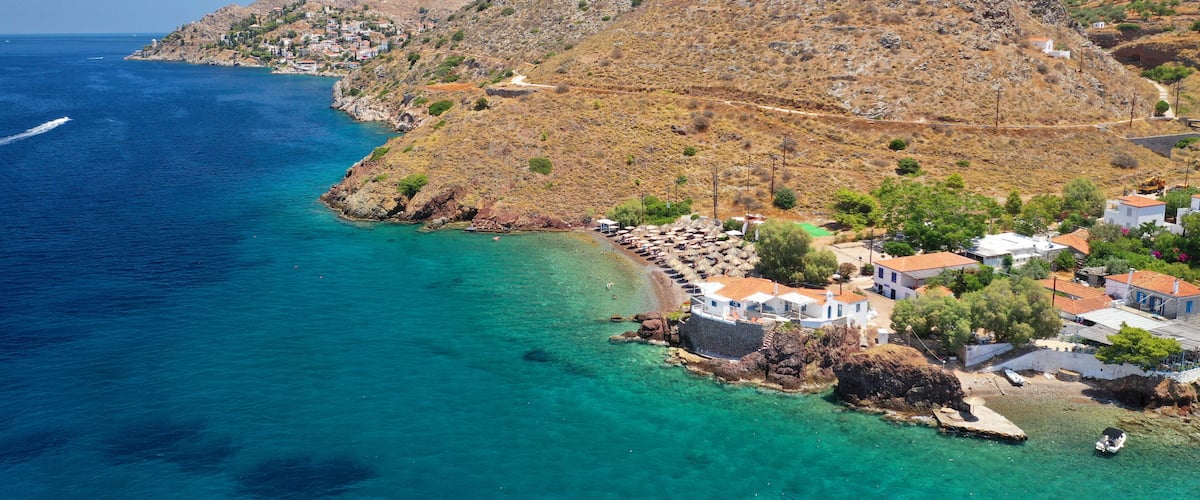 A coastal village with clear turquoise waters, terraced hills, and traditional white houses.
