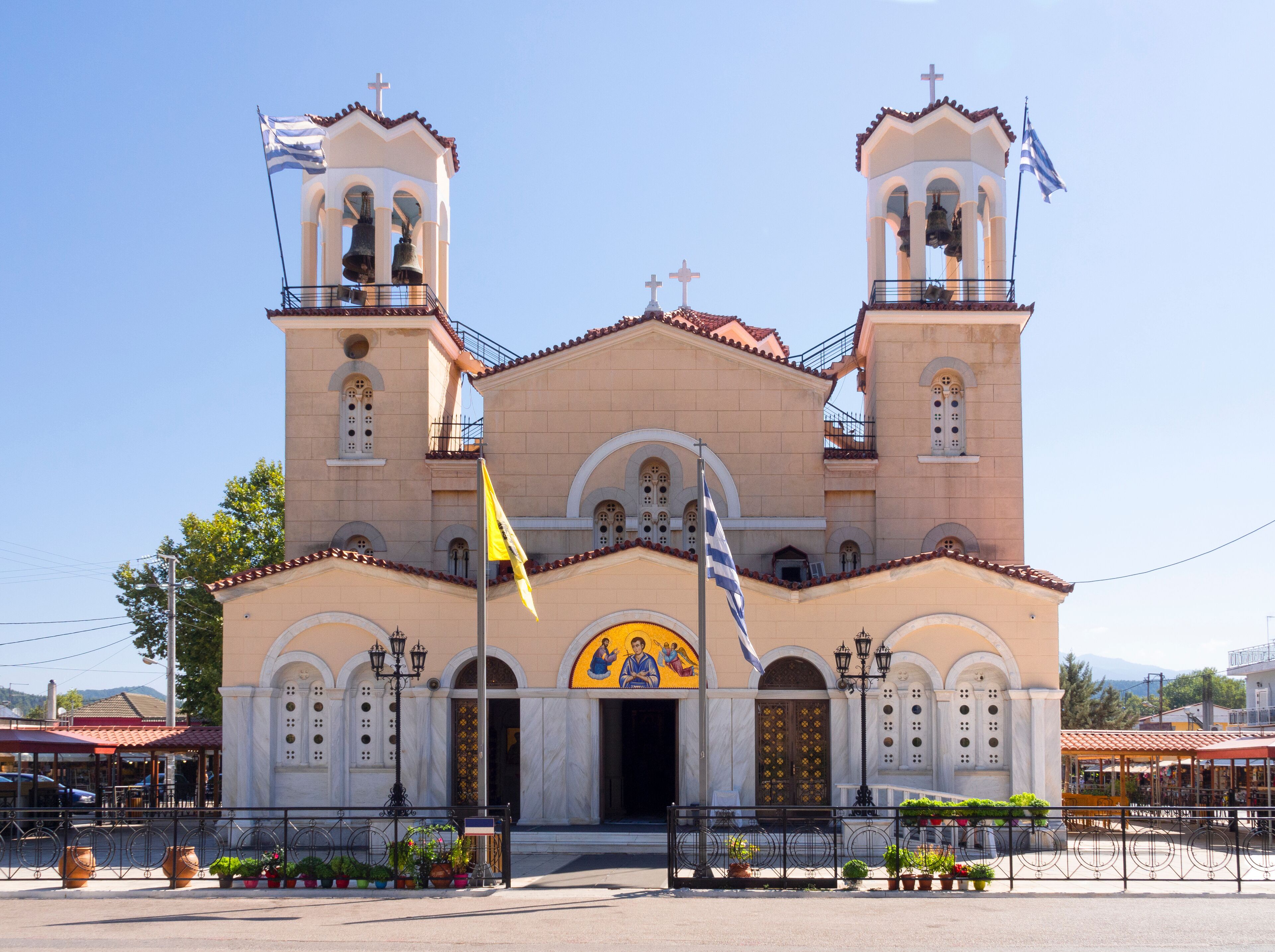 A church with two bell towers, a yellow flag, and a mural of two figures.
