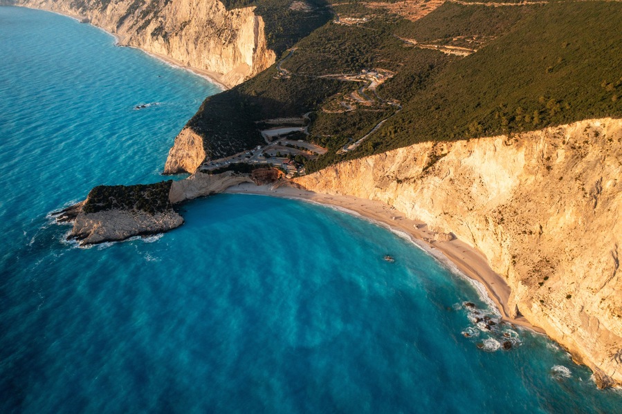 Aerial view of beautiful turquoise sea and cliffs along the coastline with a sandy beach, Athani, Greece.