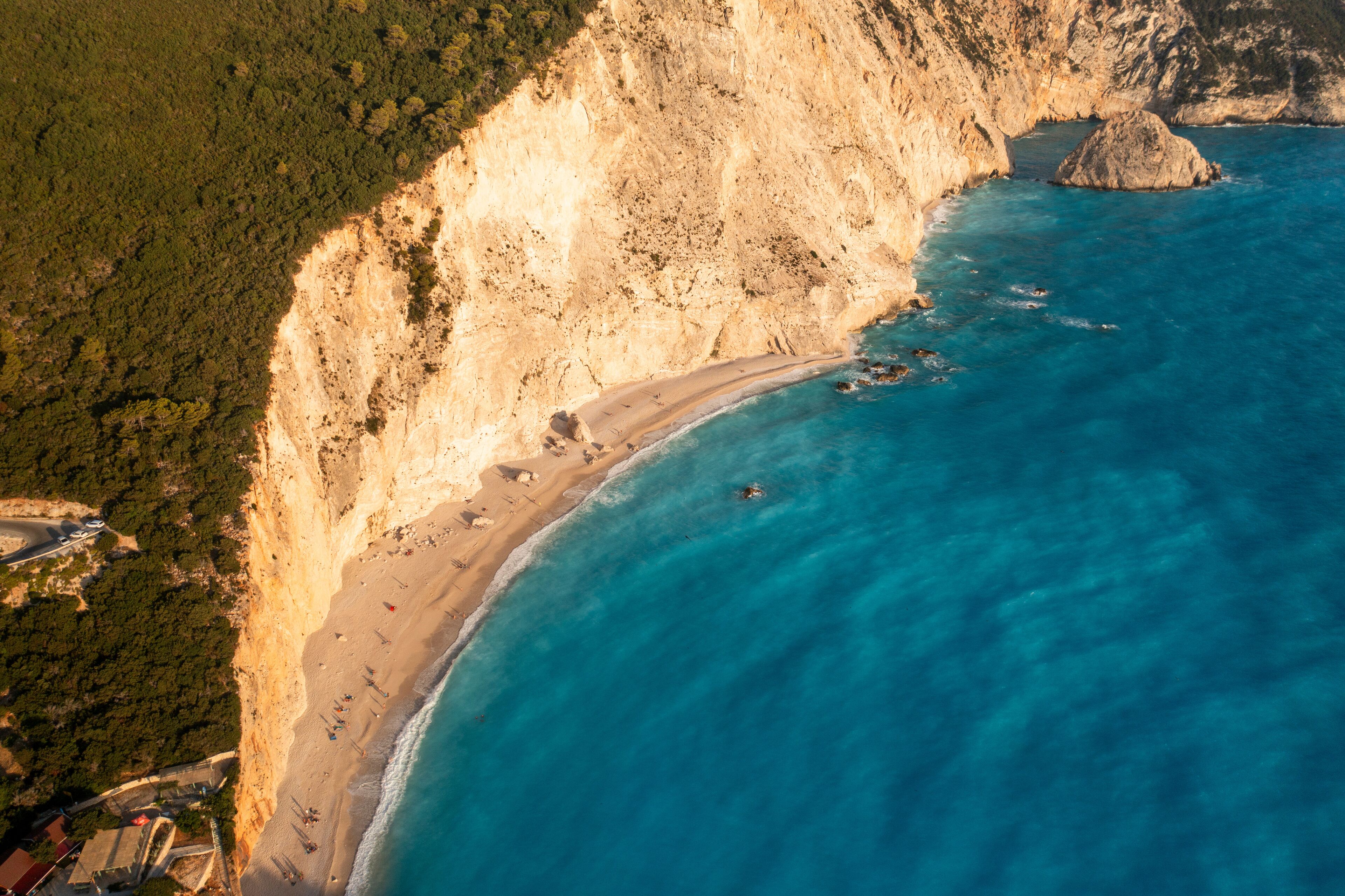 Aerial view of idyllic beach and cliff along the clear blue sea, Athani, Greece.