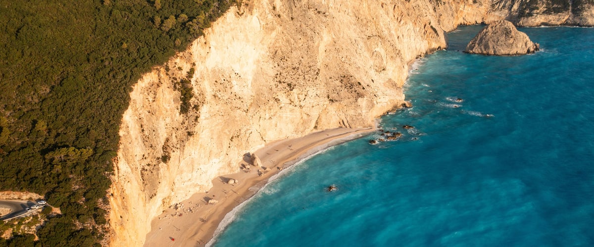 Aerial view of idyllic beach and cliff along the clear blue sea, Athani, Greece.
