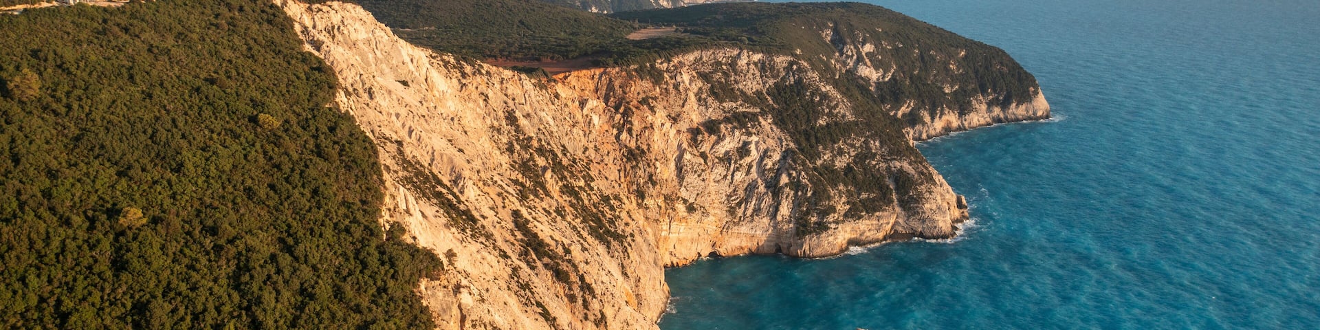 Aerial view of beautiful rocky coastline and tranquil ocean waves, Athani, Greece.