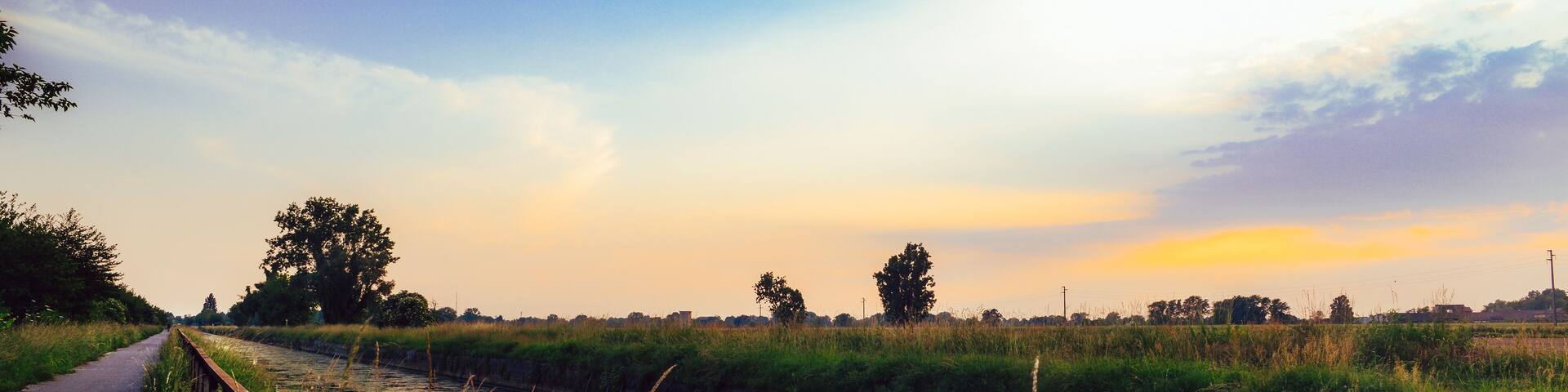 Empty cycling path along the Naviglio Pavese, canal at sunset. The canal stretches for 30km from Pavia to Milan in Lombardy, northern Italy.