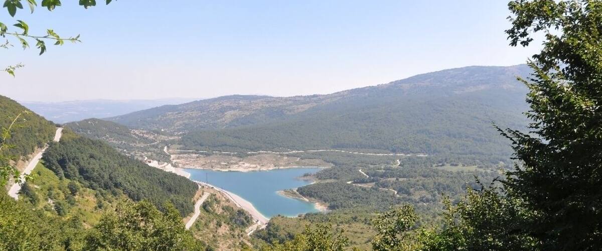 A lake surrounded by forested hills and a winding road.
