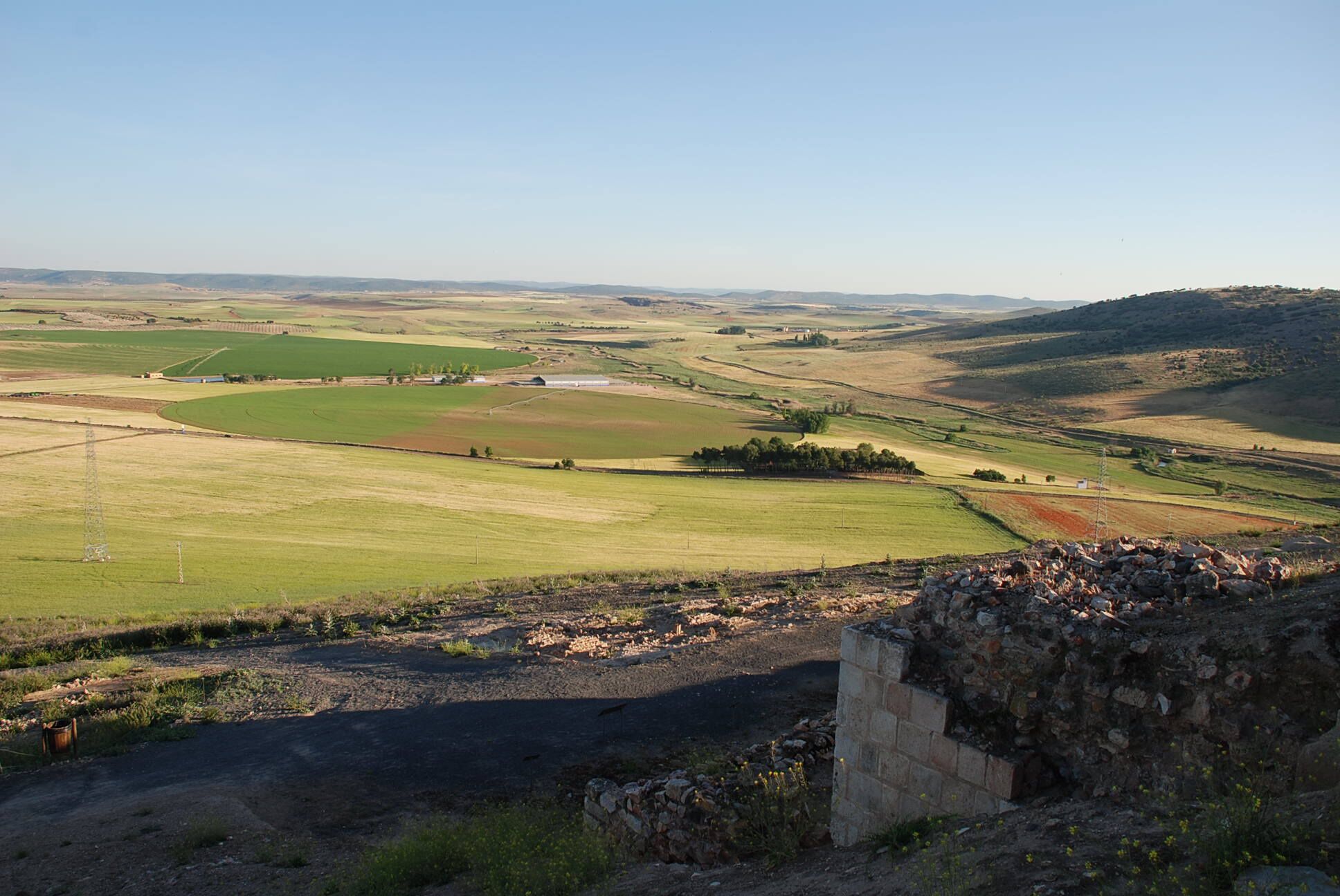 A rural landscape with rolling hills, fields, and a stone wall.