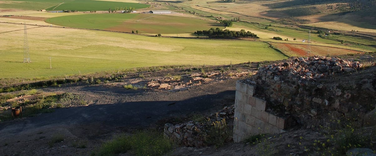A rural landscape with rolling hills, fields, and a stone wall.
