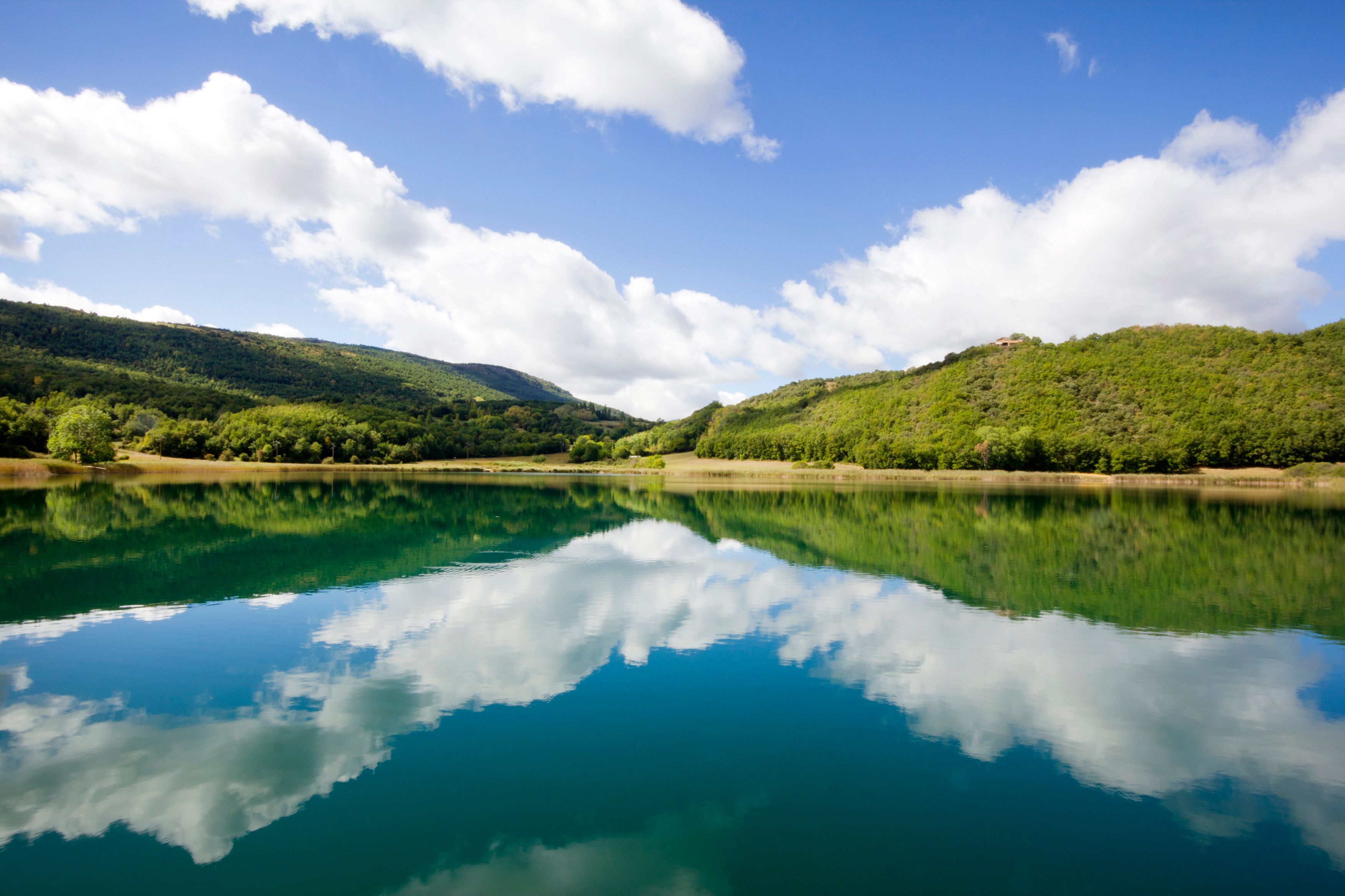 Un lago sereno que refleja el cielo y las colinas circundantes.