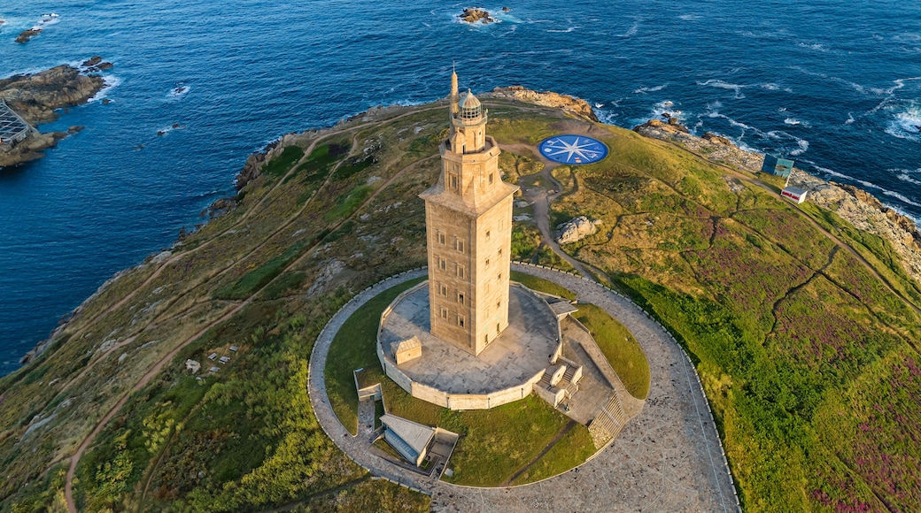 A lighthouse on a rocky coastline with a circular walkway and a small building nearby.