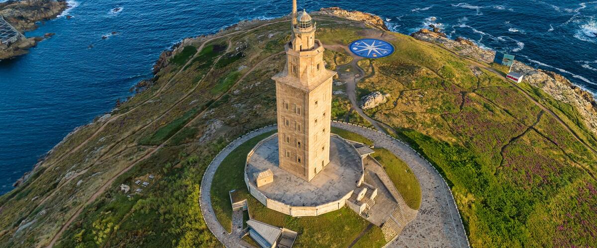 Ein Leuchtturm an einer felsigen Küste mit einem kreisförmigen Rundgang und einem kleinen Gebäude in der Nähe.