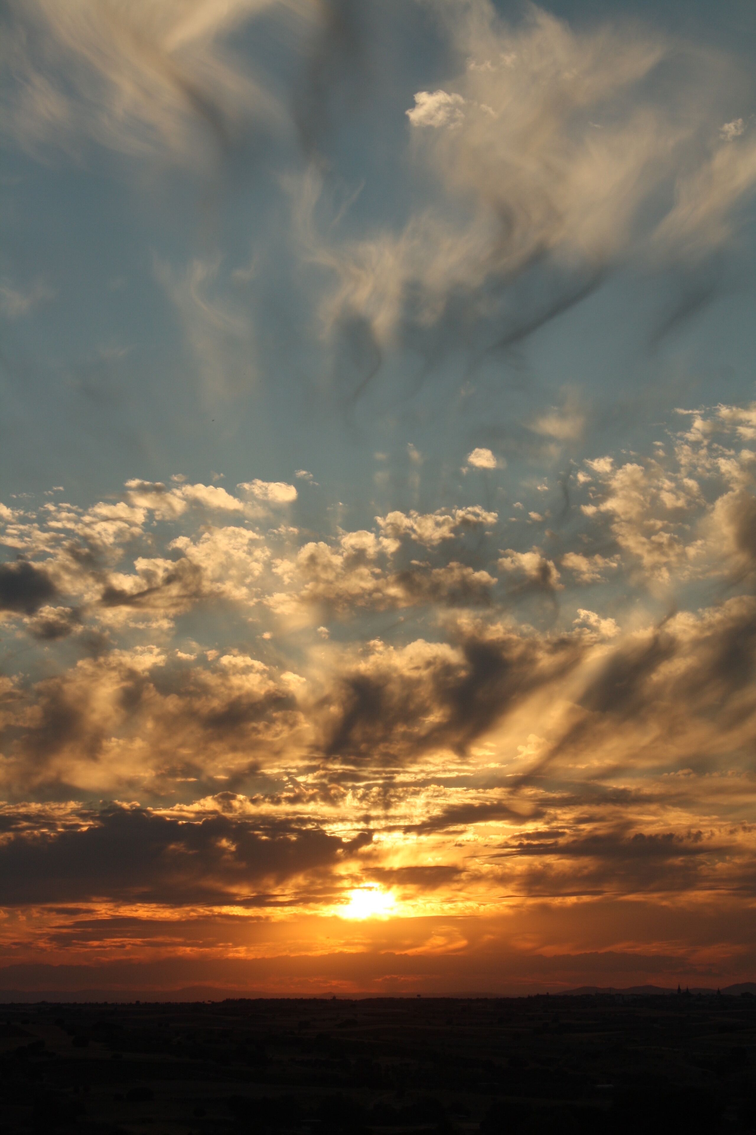 A sunset with clouds over a flat landscape.