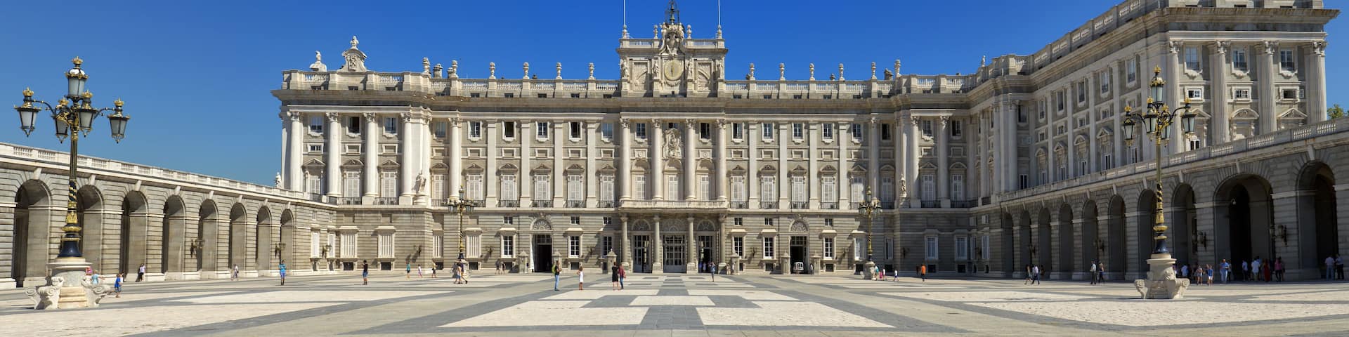 A grand historic building with classical architecture, featuring columns, statues, and a large central courtyard.