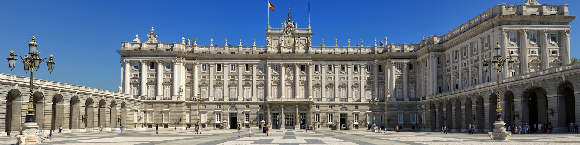 Um edifício histórico imponente com arquitetura clássica, apresentando colunas, esculturas e um amplo pátio central.