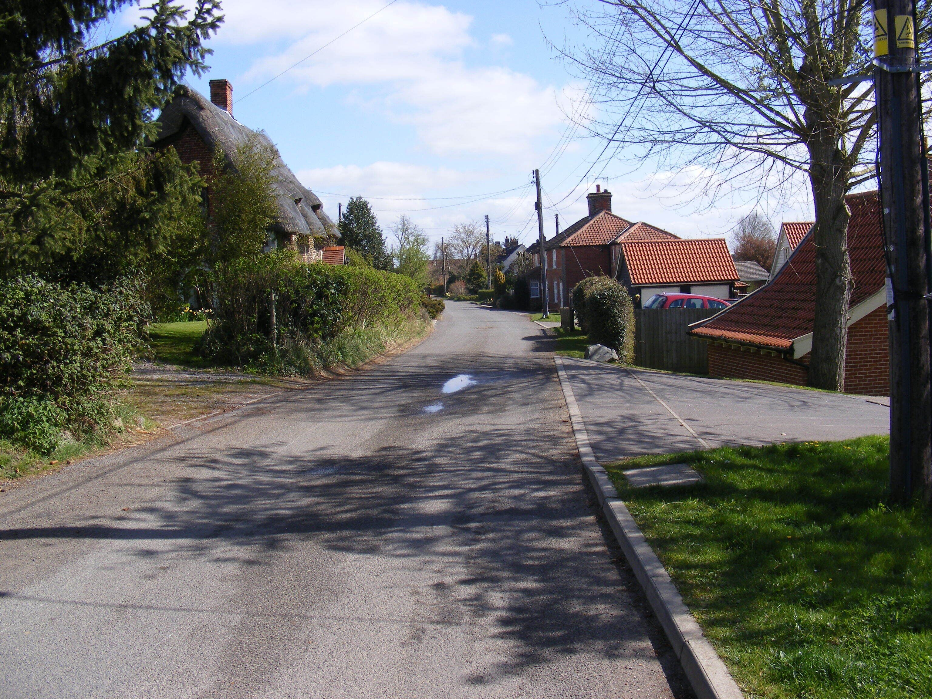 A quiet suburban street lined with houses and trees.
