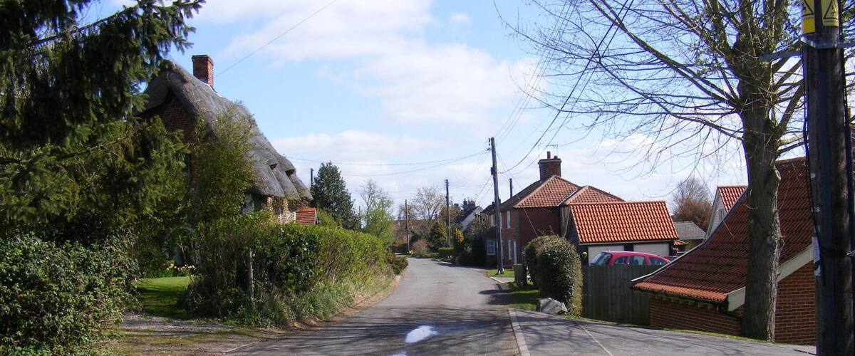 A quiet suburban street lined with houses and trees.