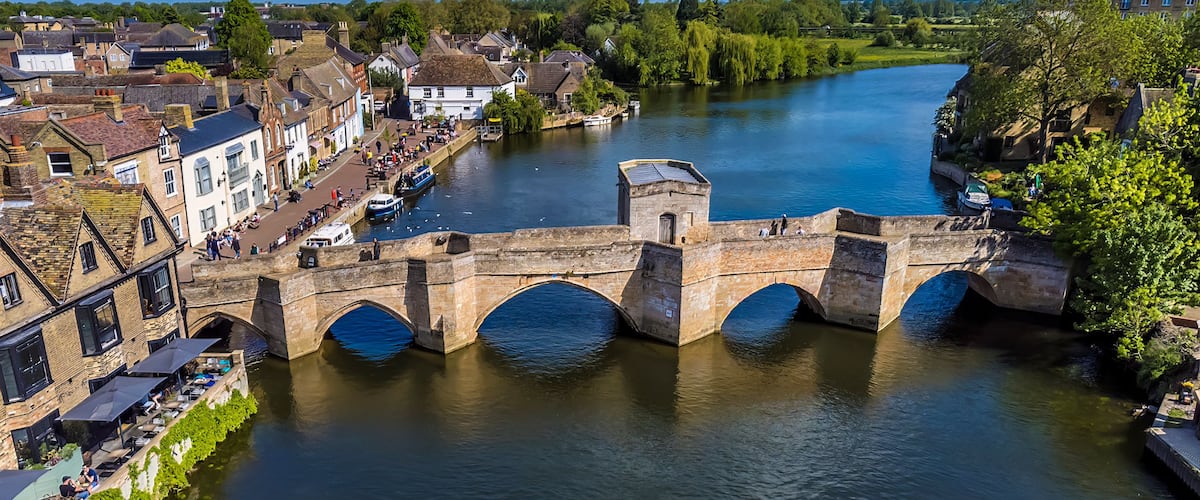 Un puente de piedra sobre un río, rodeado de edificios históricos y vegetación.