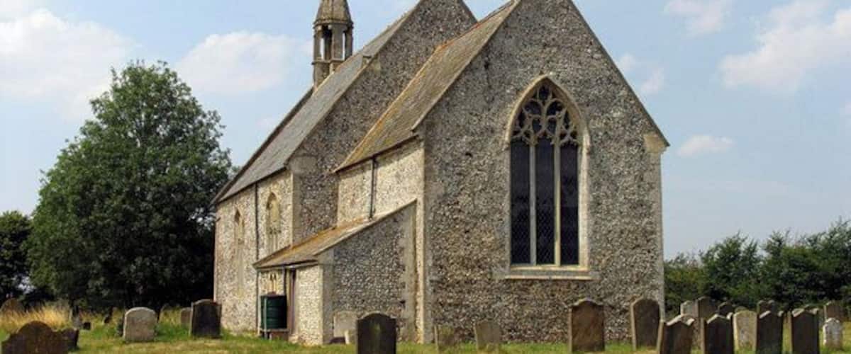 A stone church with a bell tower and a graveyard.