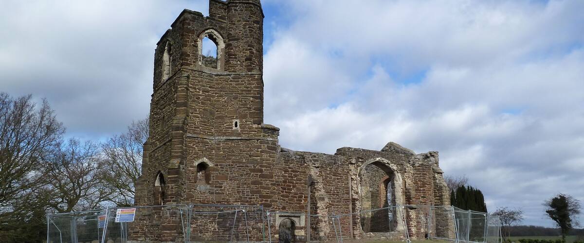 An old stone church with a tall bell tower and arched windows.