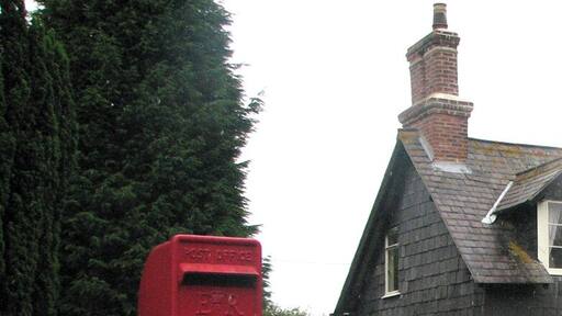 Teigh: postbox E II R postbox on a stick and some bright borders, on a showery afternoon.
