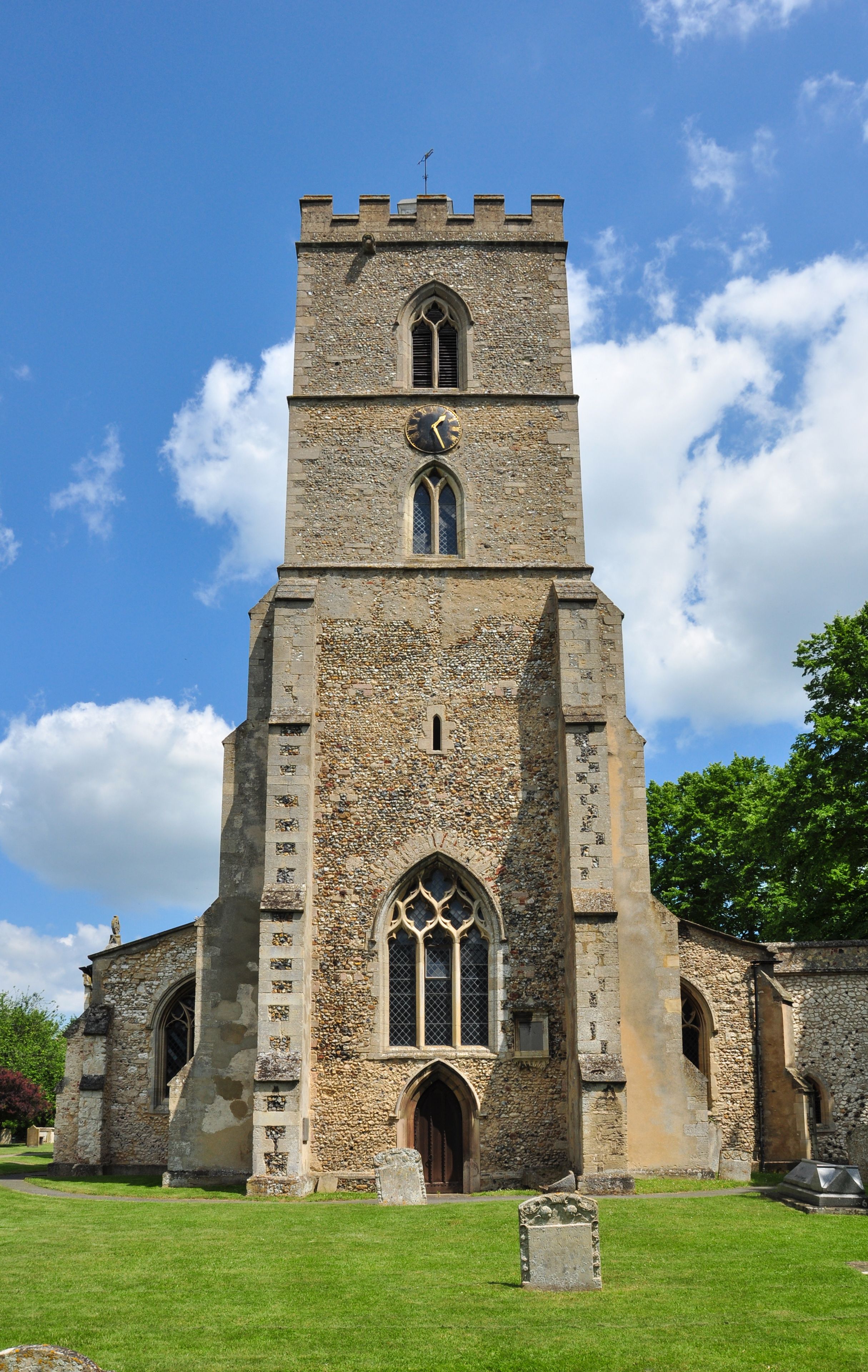 A historic stone church with a tall bell tower, arched windows, and a clear blue sky.