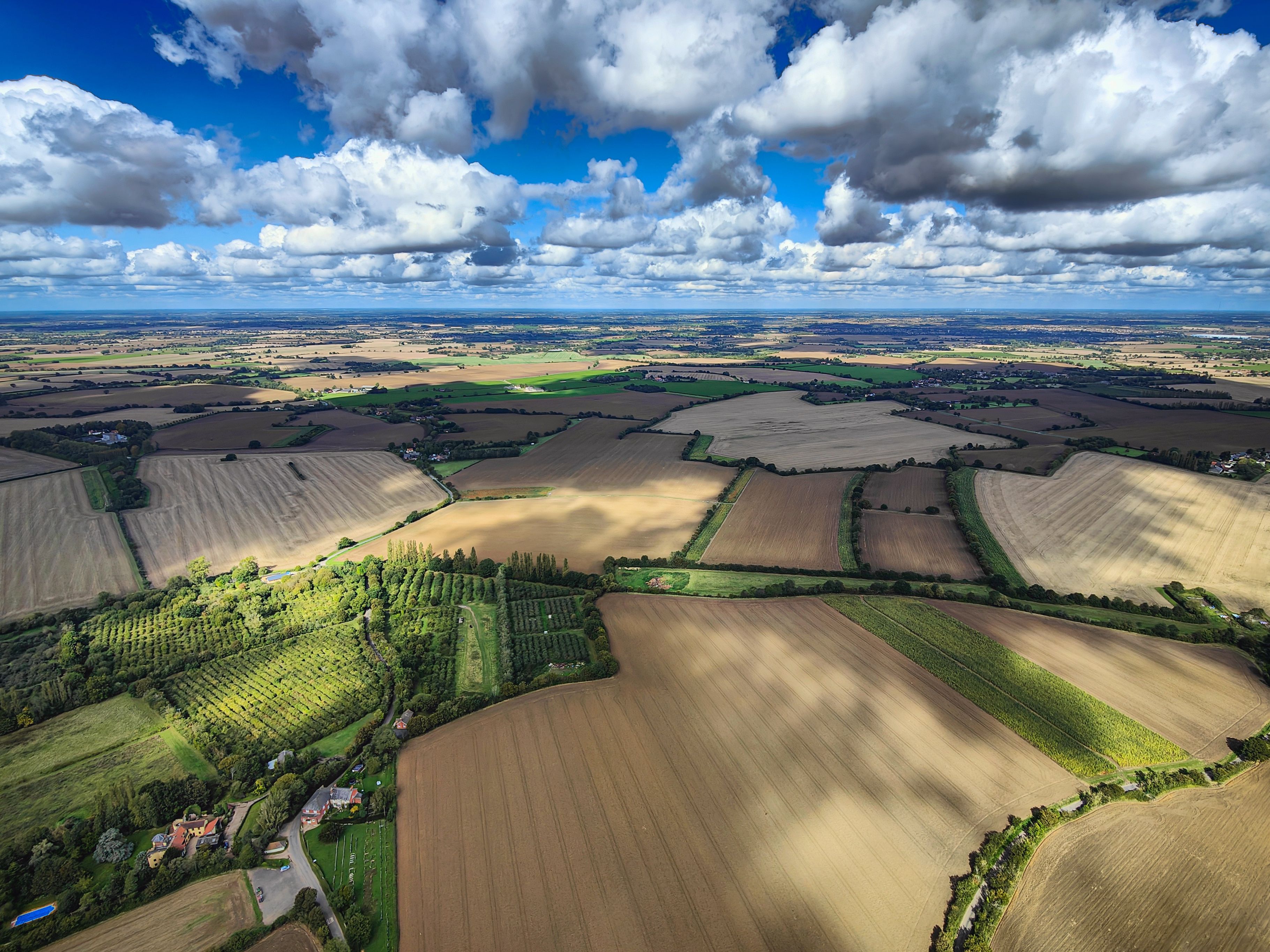 An aerial view of a rural landscape with fields, trees, and scattered houses.