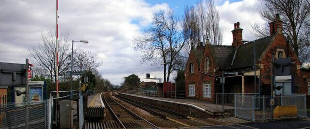 A railway crossing with tracks, a platform, and a brick building.