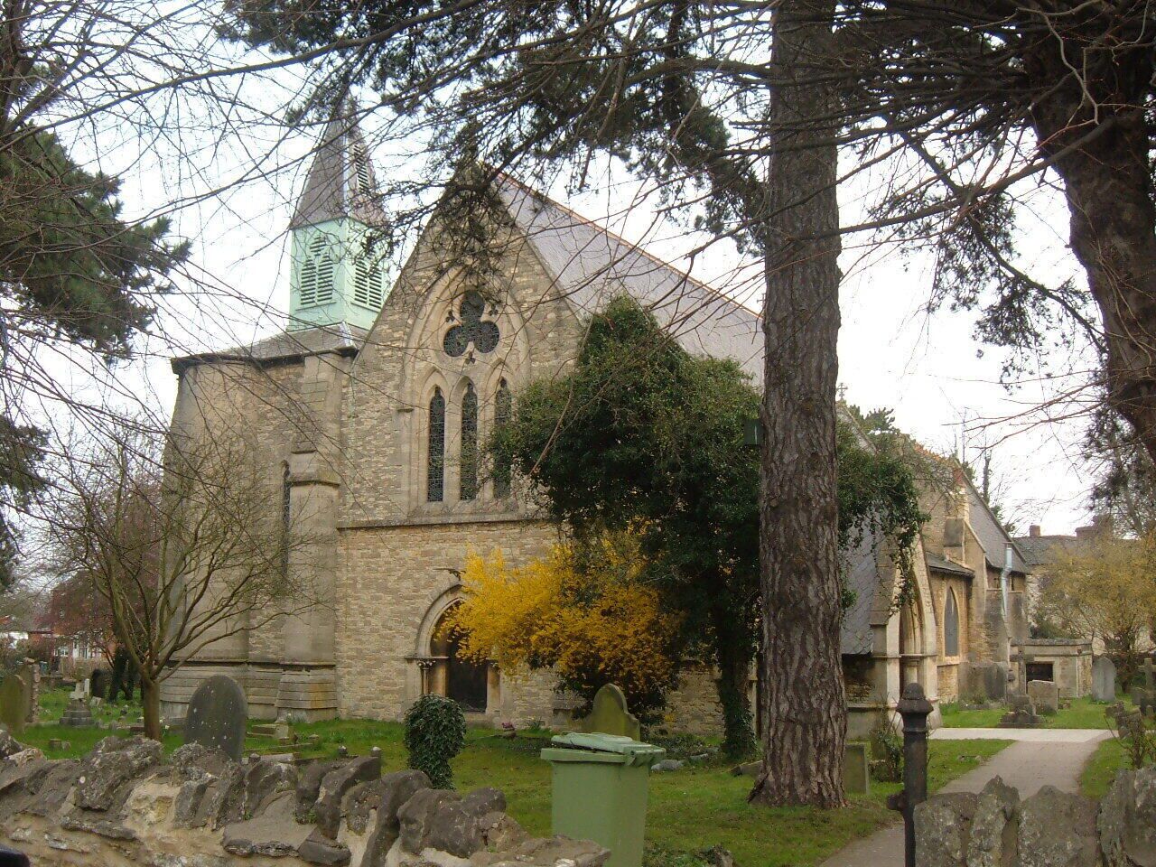 A stone church with a tall steeple and a large stained glass window.