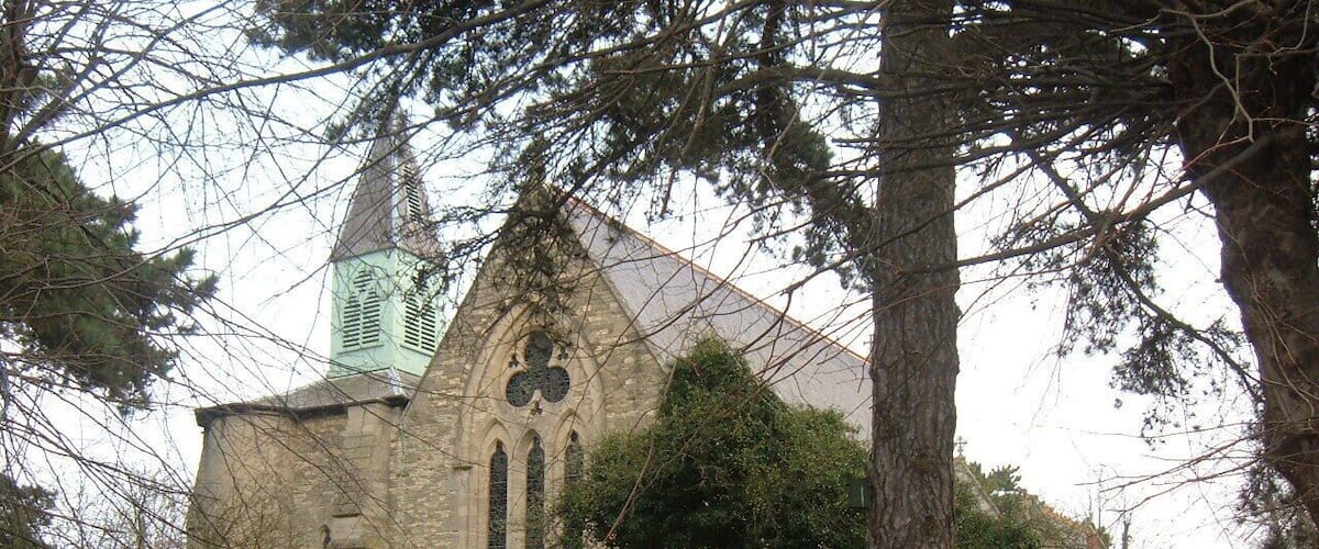 A stone church with a tall steeple and a large stained glass window.