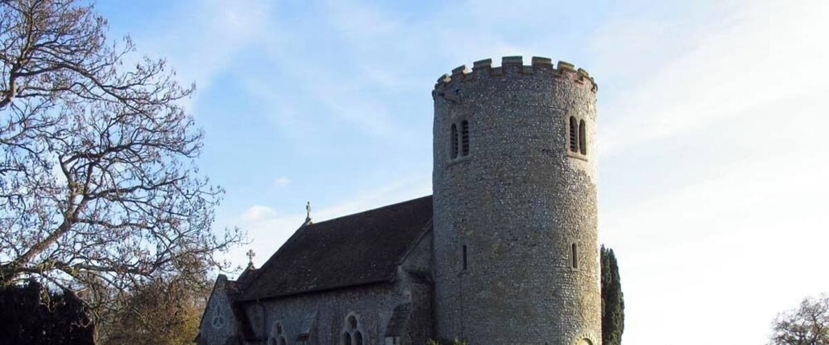 A stone church with a round tower and a cemetery.