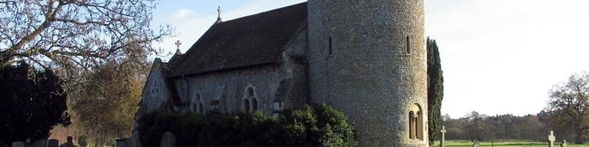 A stone church with a round tower and a cemetery.