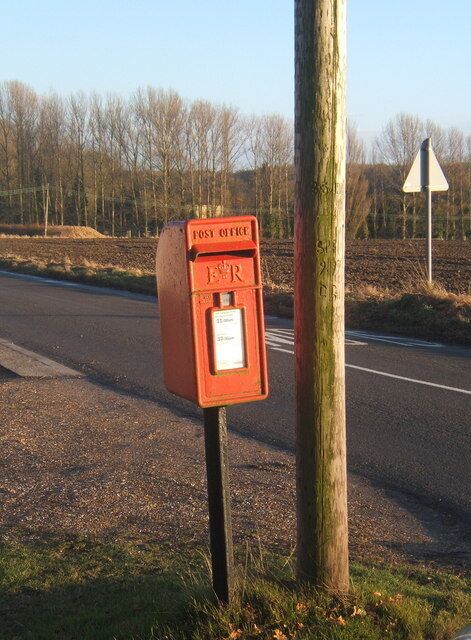 A red post office mailbox on a roadside.