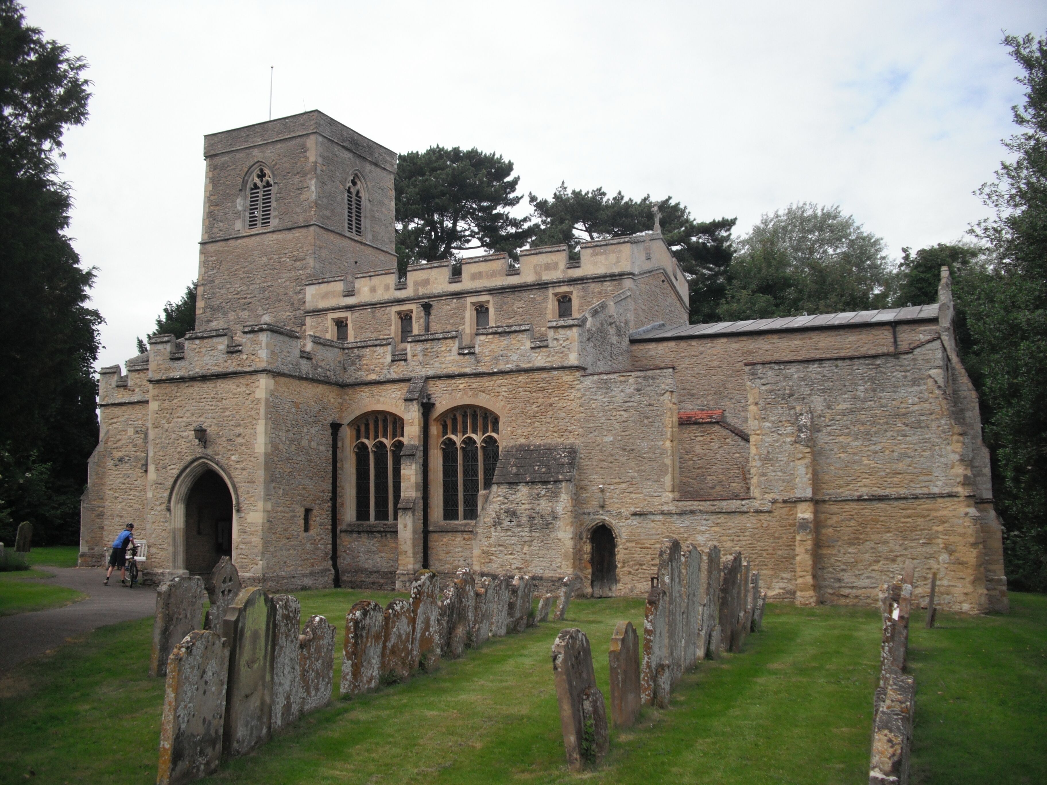 A historic stone church with a bell tower and a graveyard in front.