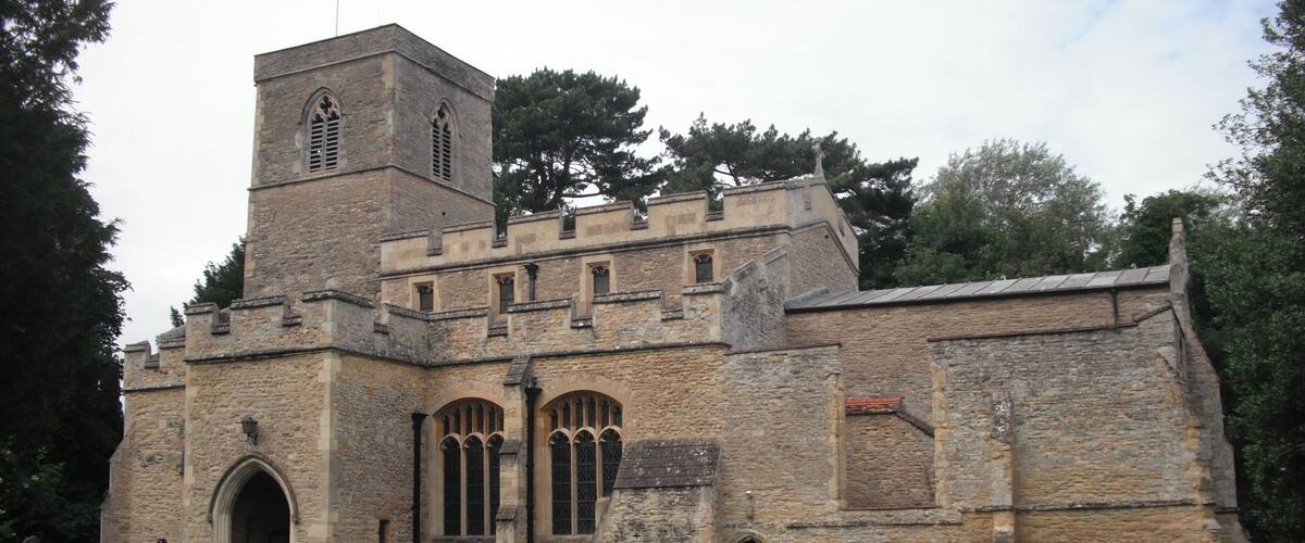 A historic stone church with a bell tower and a graveyard in front.