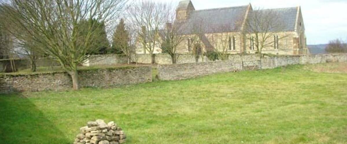A stone building with a grassy field and a pile of stones in the foreground.
