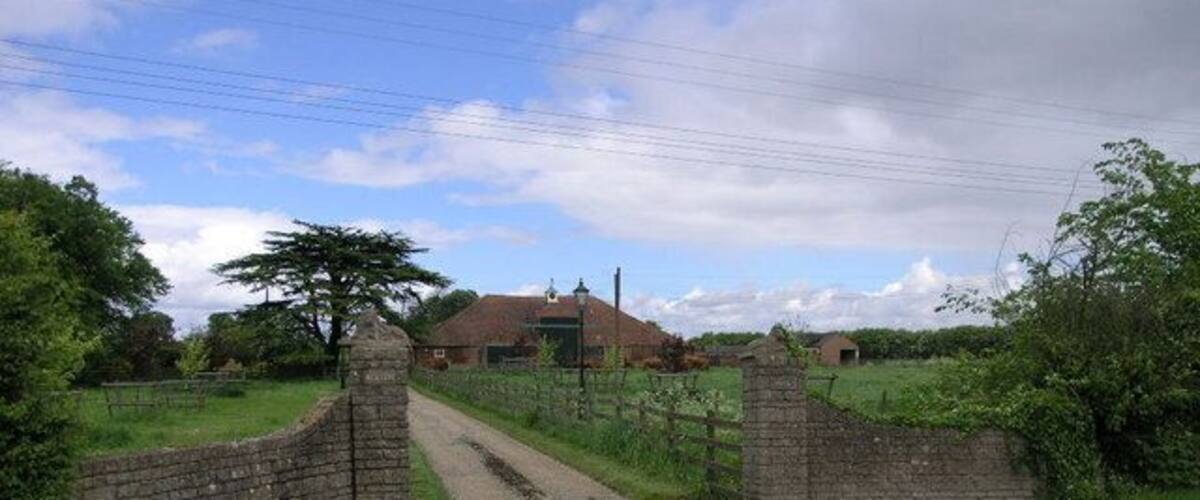 A rural road with a stone gate leading to a house.