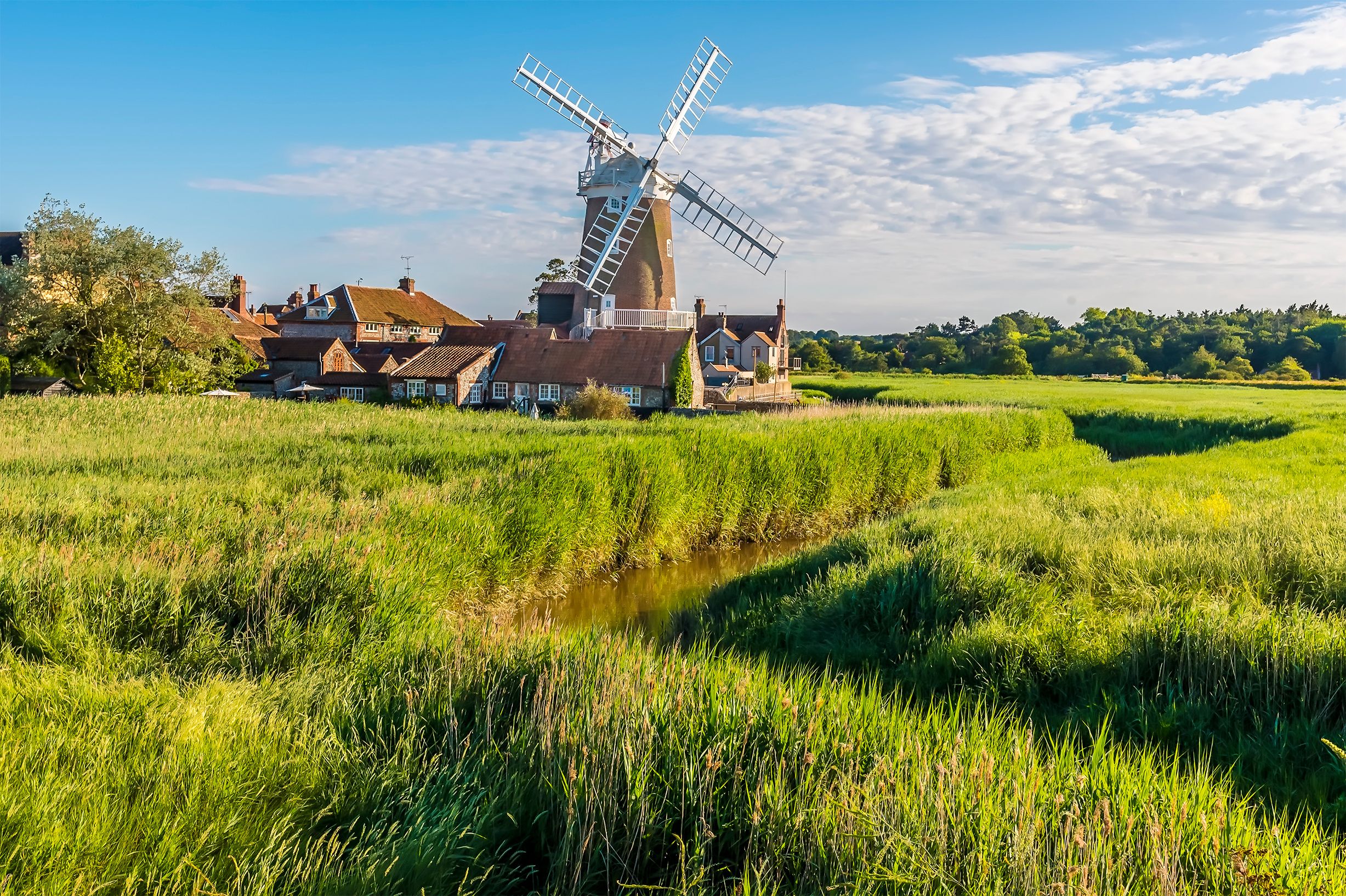 Eine traditionelle Windmühle in einem üppigen, grünen Feld mit einem kleinen Bach.