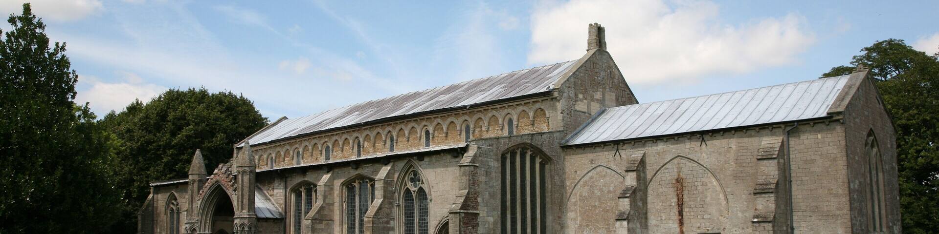 A historic church with arched windows and a graveyard in front.