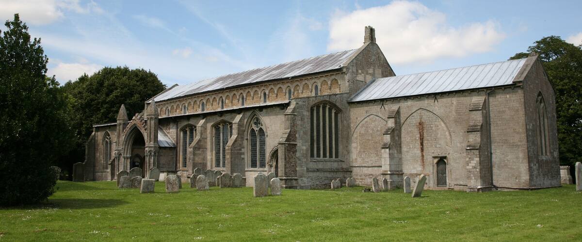 A historic church with arched windows and a graveyard in front.