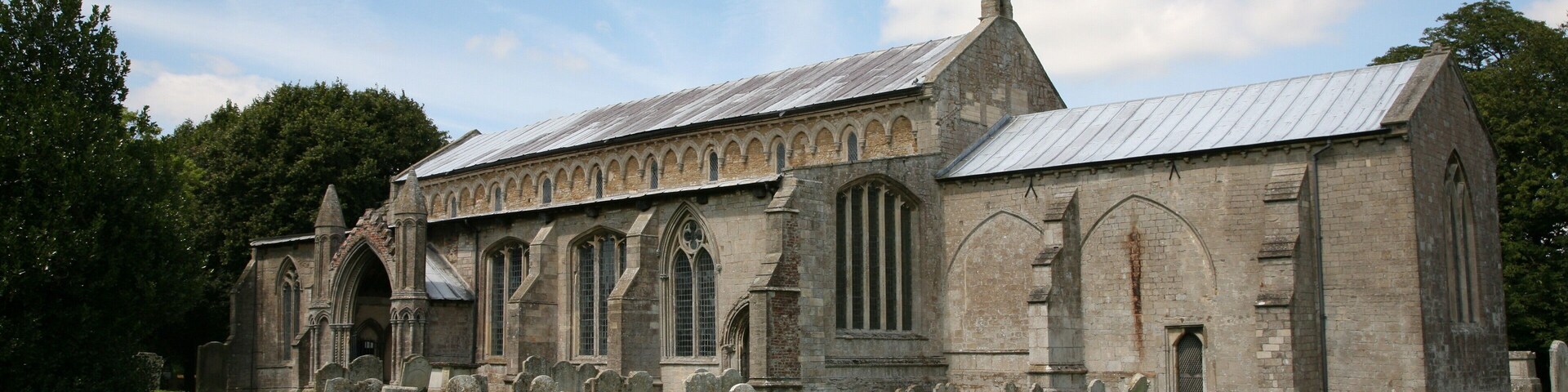 A historic church with arched windows and a graveyard in front.