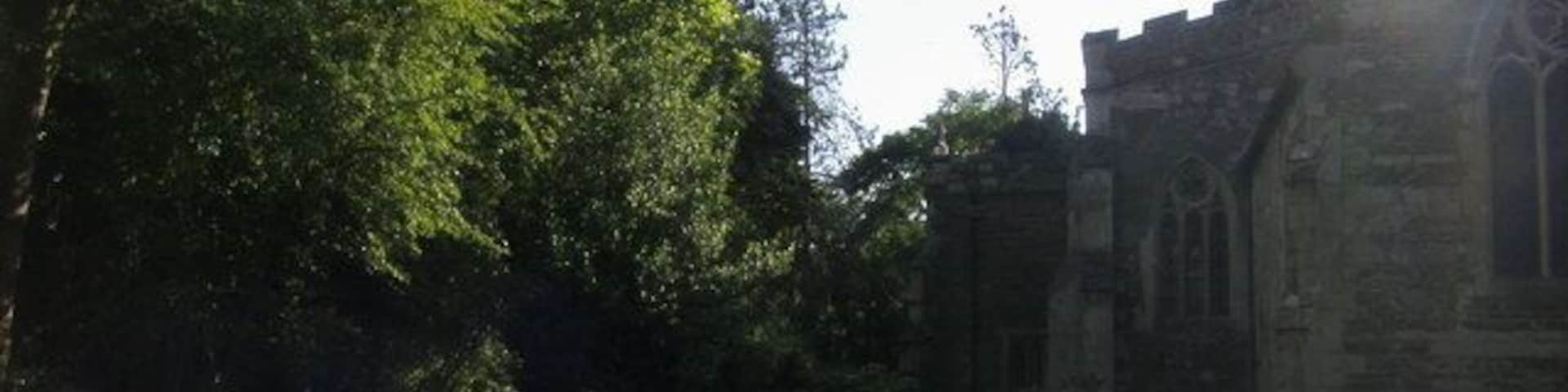 A historic church with a spire, surrounded by lush greenery and a well-maintained lawn.