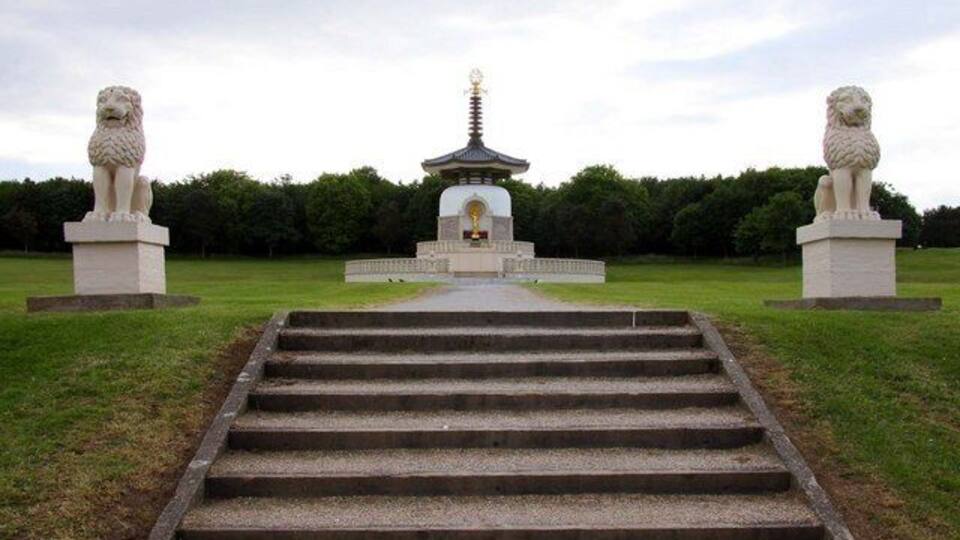 Un temple amb una pagoda, envoltat d'estàtues i un camí.