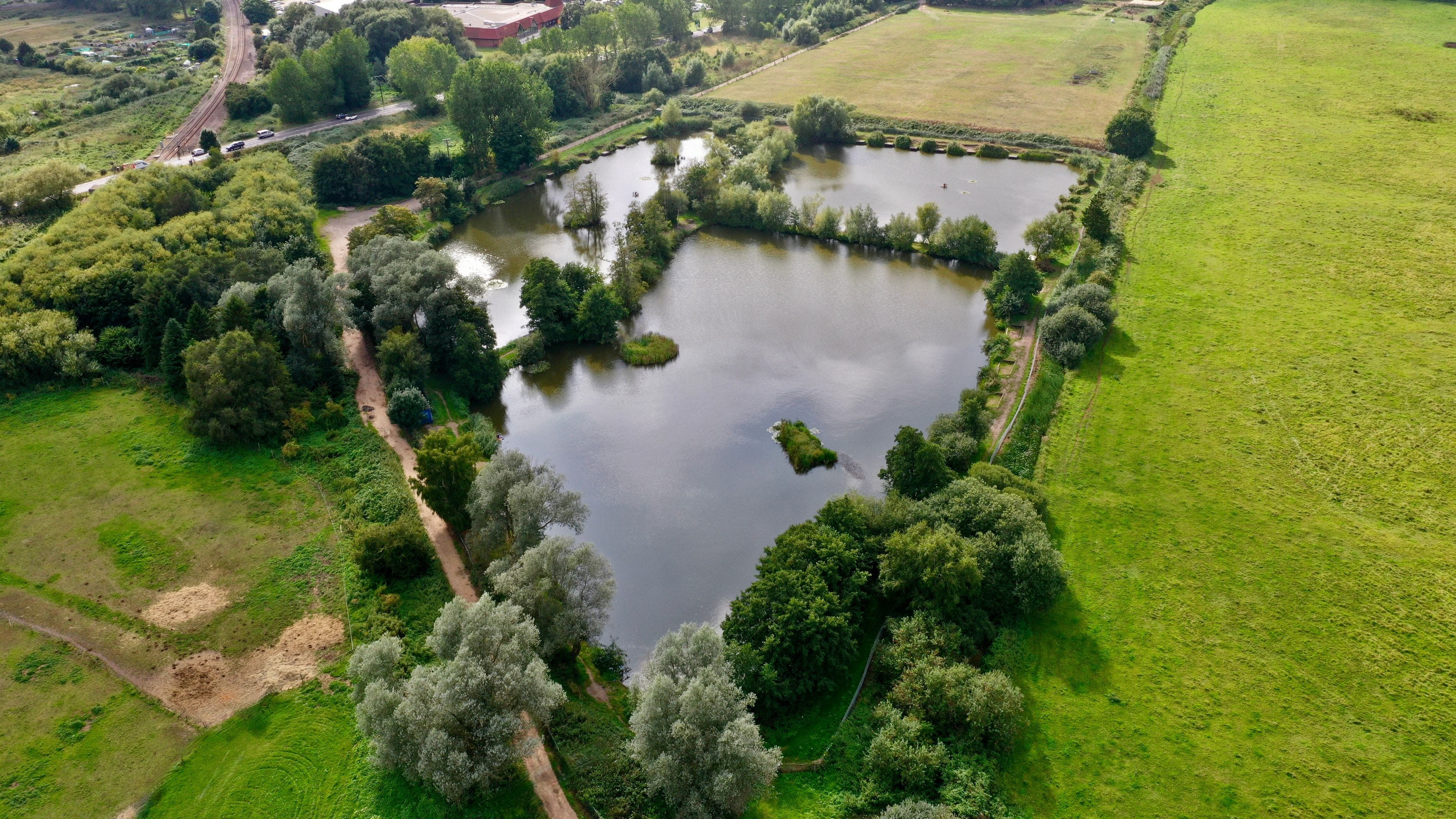 An aerial view of a lake surrounded by trees and grassy fields.