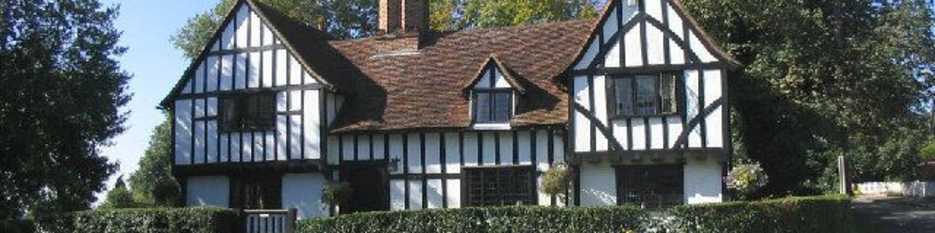 A Tudor-style house with a steeply pitched roof and white timber framing.