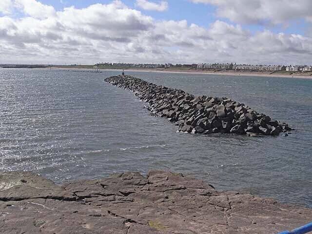 Breakwater, Newbiggin Bay. The two breakwaters at the mouth of Newbiggin Bay were constructed in 2007 to conserve the beach. It is possible to make out the sculpture, Couple on the far breakwater. See 1484759 and other images..