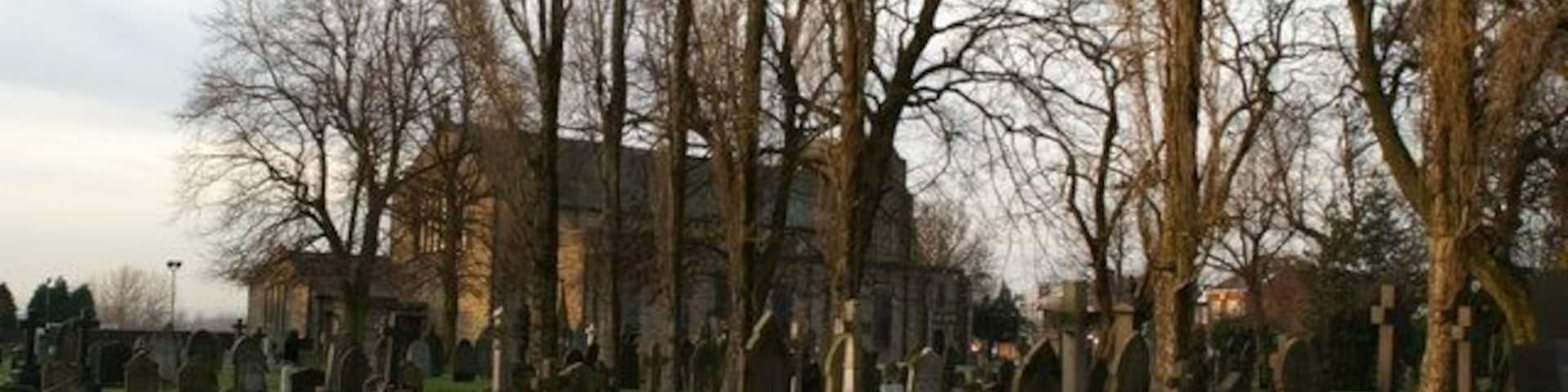 A cemetery with numerous tombstones and bare trees.