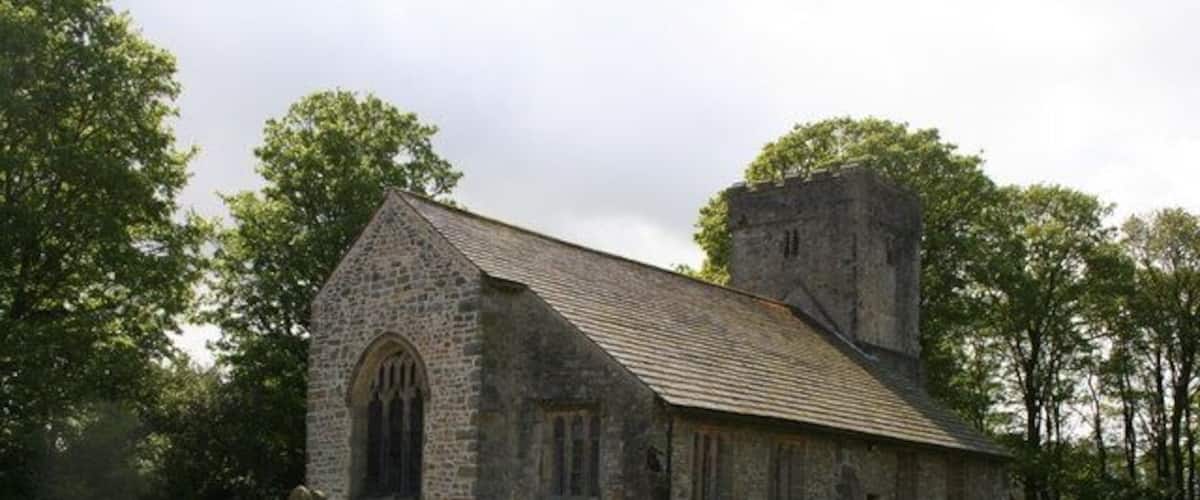 A stone church with a tower and a graveyard with headstones.