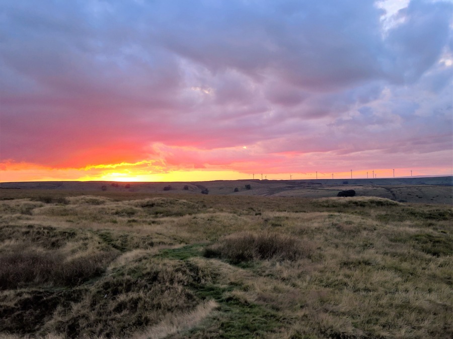 On the summit plateau of Musbury Tor, next to the disused quarry at the eastern end at sunset. Hyndburn Wind Farm can be seen on the horizon.