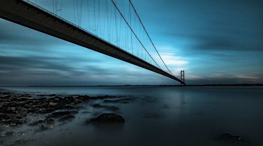 Un puente sobre aguas tranquilas con una orilla rocosa.