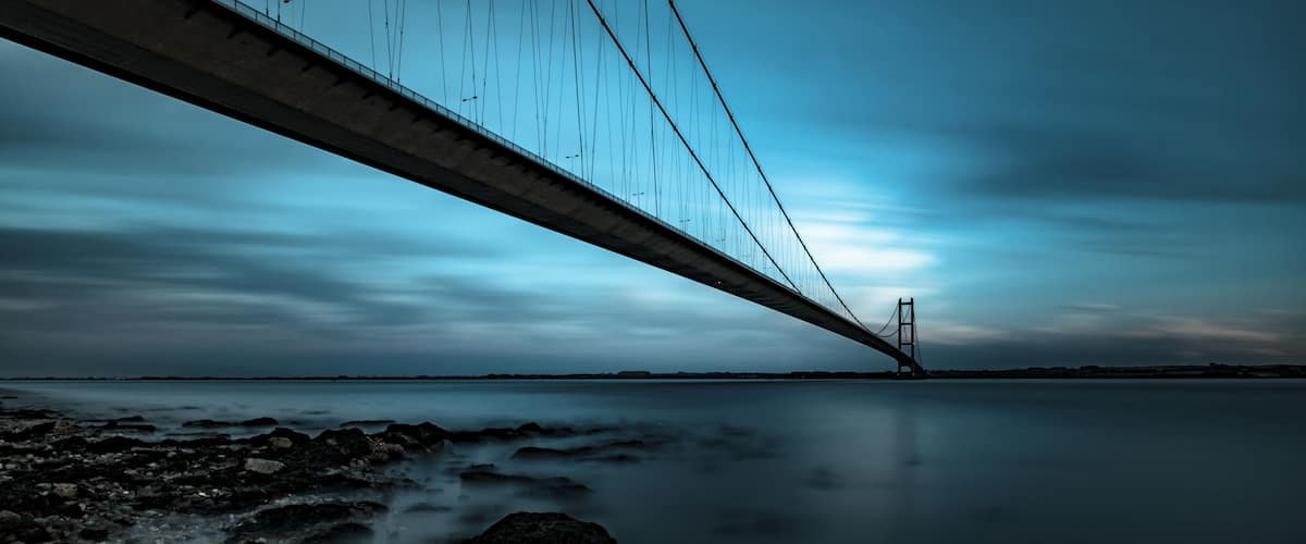 Un puente sobre aguas tranquilas con una orilla rocosa.