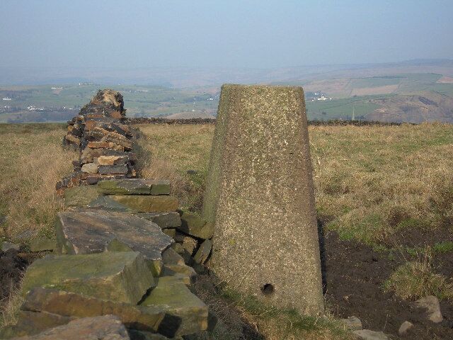 Hey Farm triangulation pillar, 253 metres. Situated just off the Crompton Circuit circular walk not far from Whitfield Hall. Flush bracket no.S2788. View looking north - The spire of Newhey Parish Church can just be seen peeping above the wall to the right of the trig pillar.